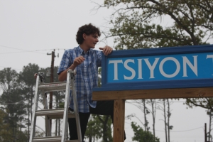 Jacob helps put up Tsiyon Tabernacle sign.